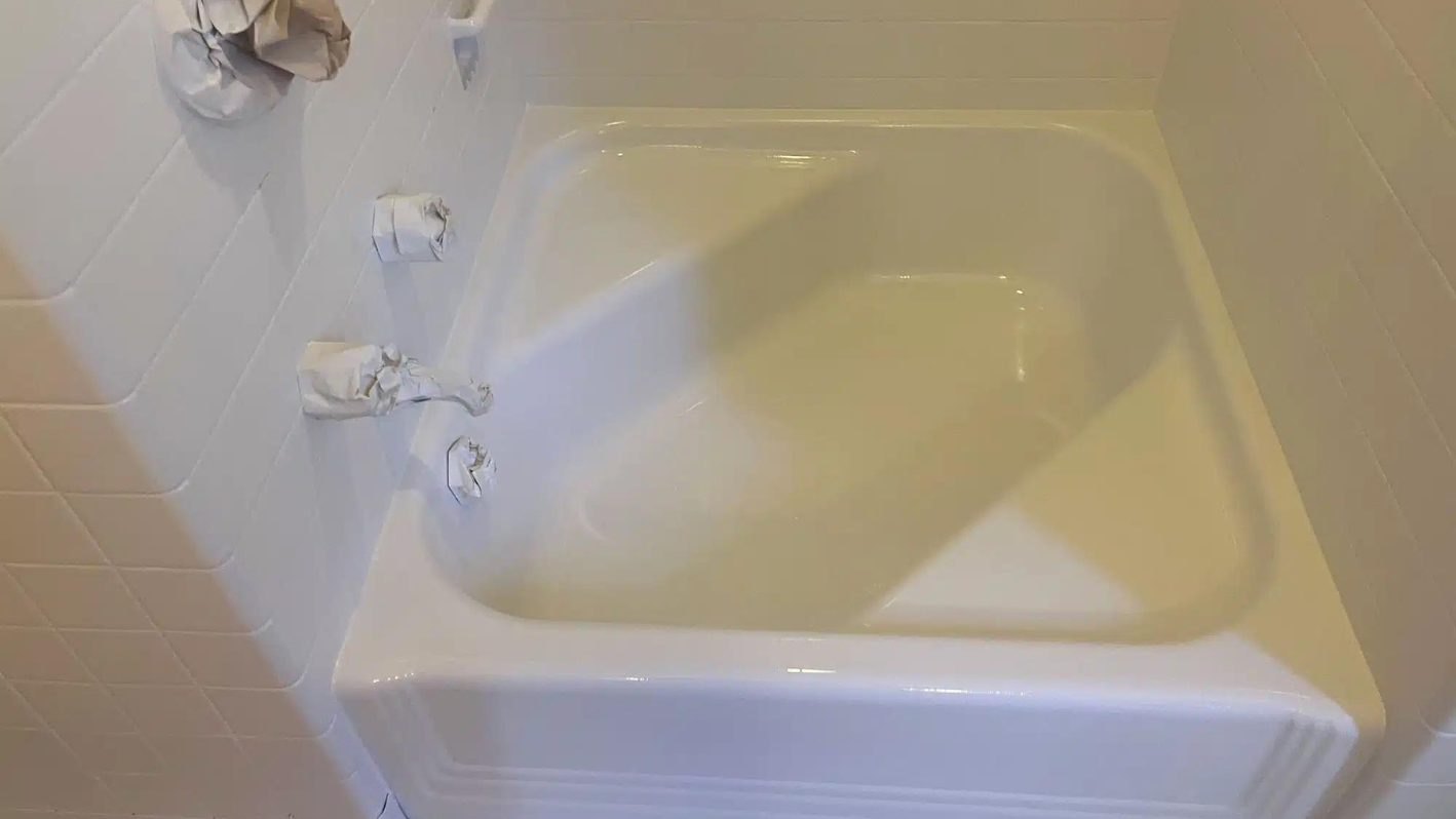 A white bath tub sitting next to a toilet paper dispenser